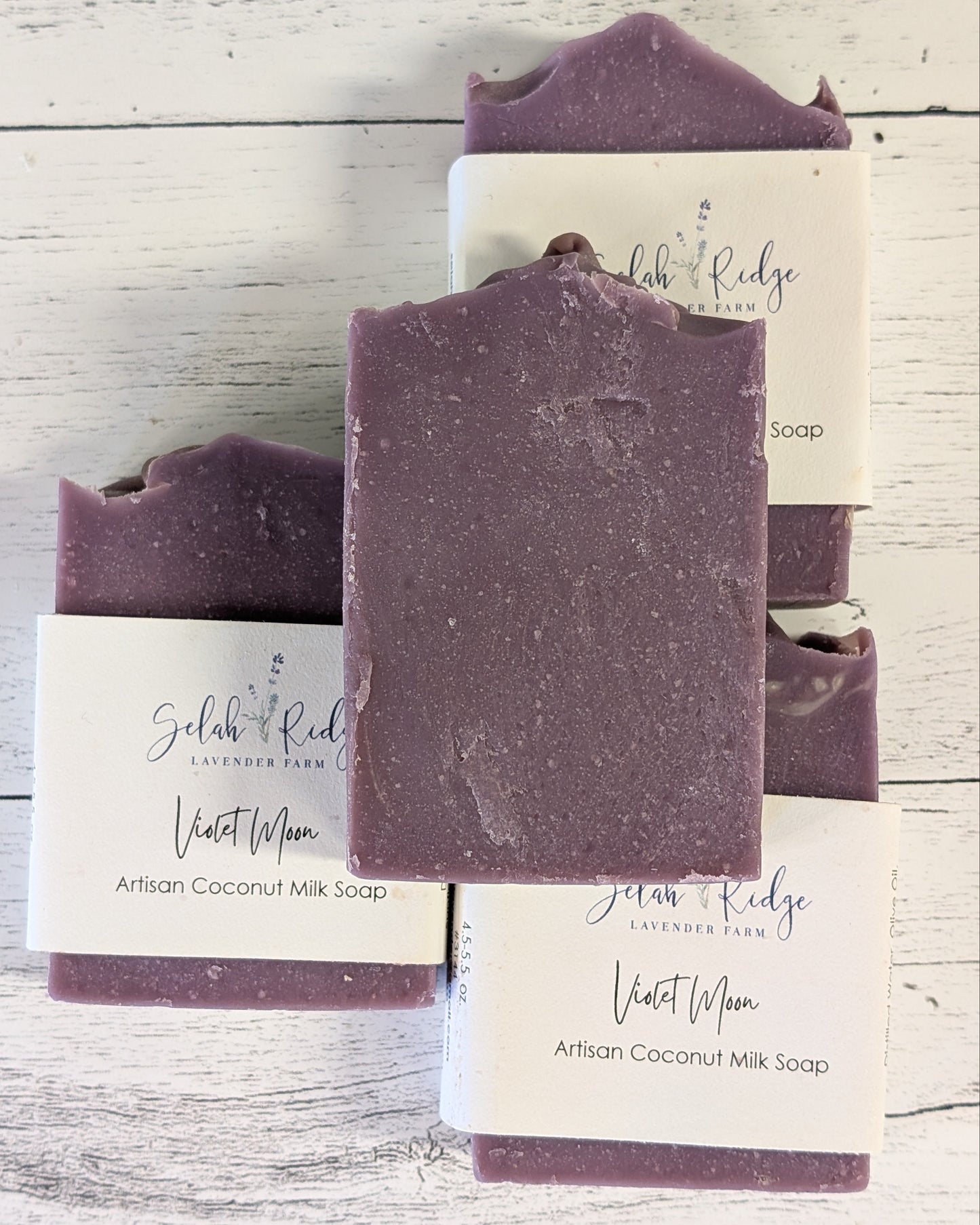 Purple soap bars with white labels on a wooden surface