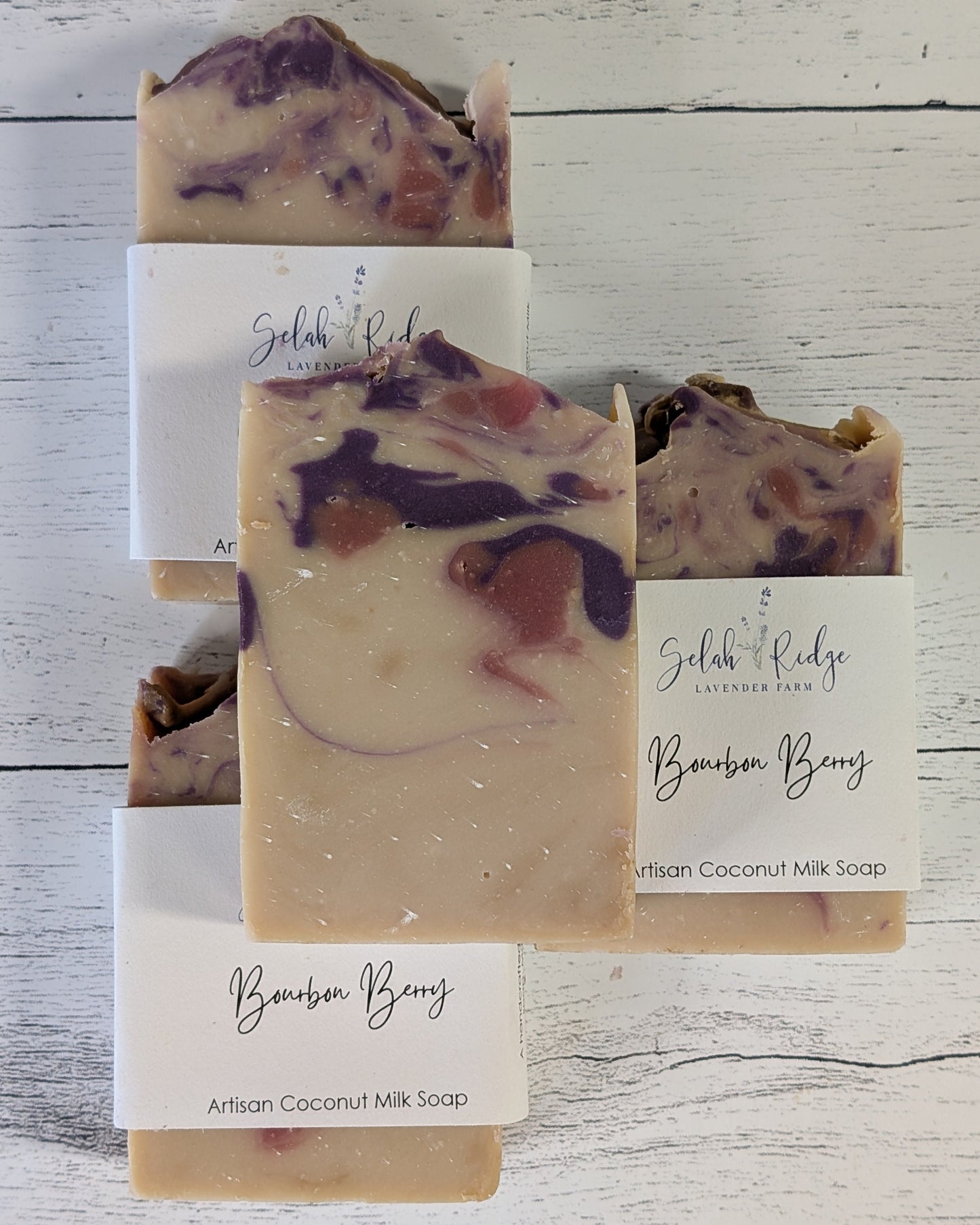 Three bars of 'Bourbon Berry' soap with visible ingredients on a white background