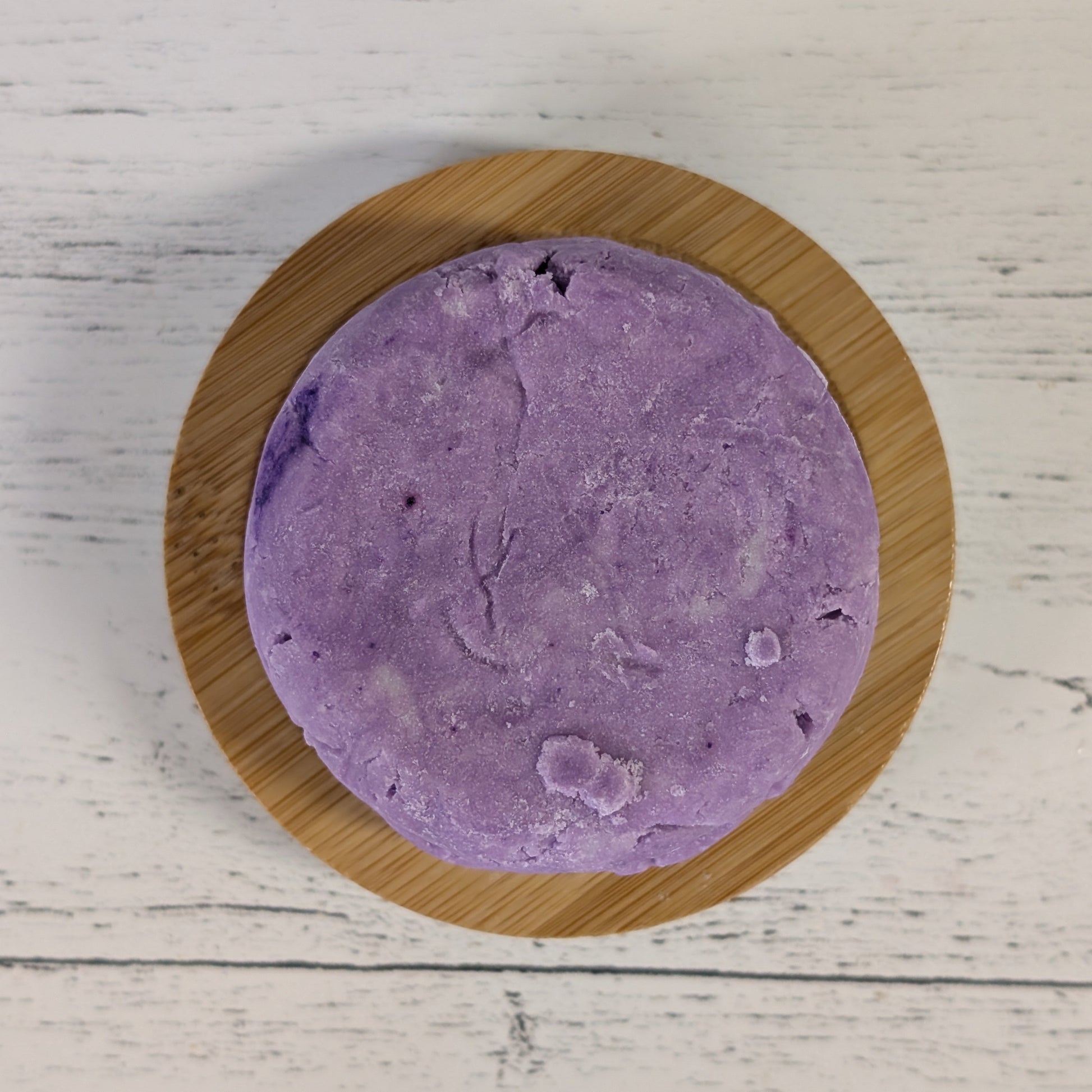 purple round lavender shampoo bar on bamboo soap tray