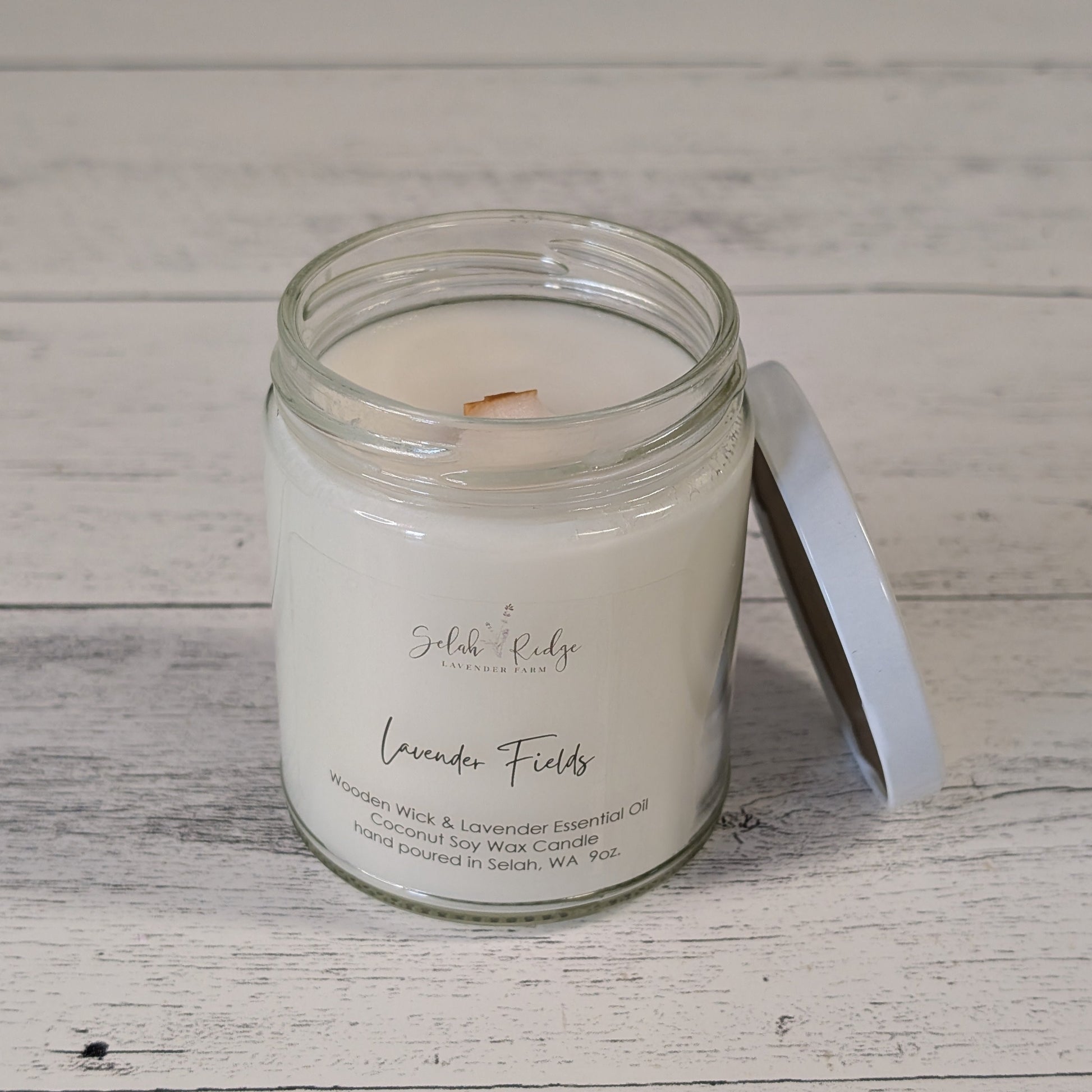 Candle in a glass jar with a white lid on a wooden surface
